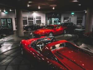 Red Ferrari sports cars on display in a museum setting.