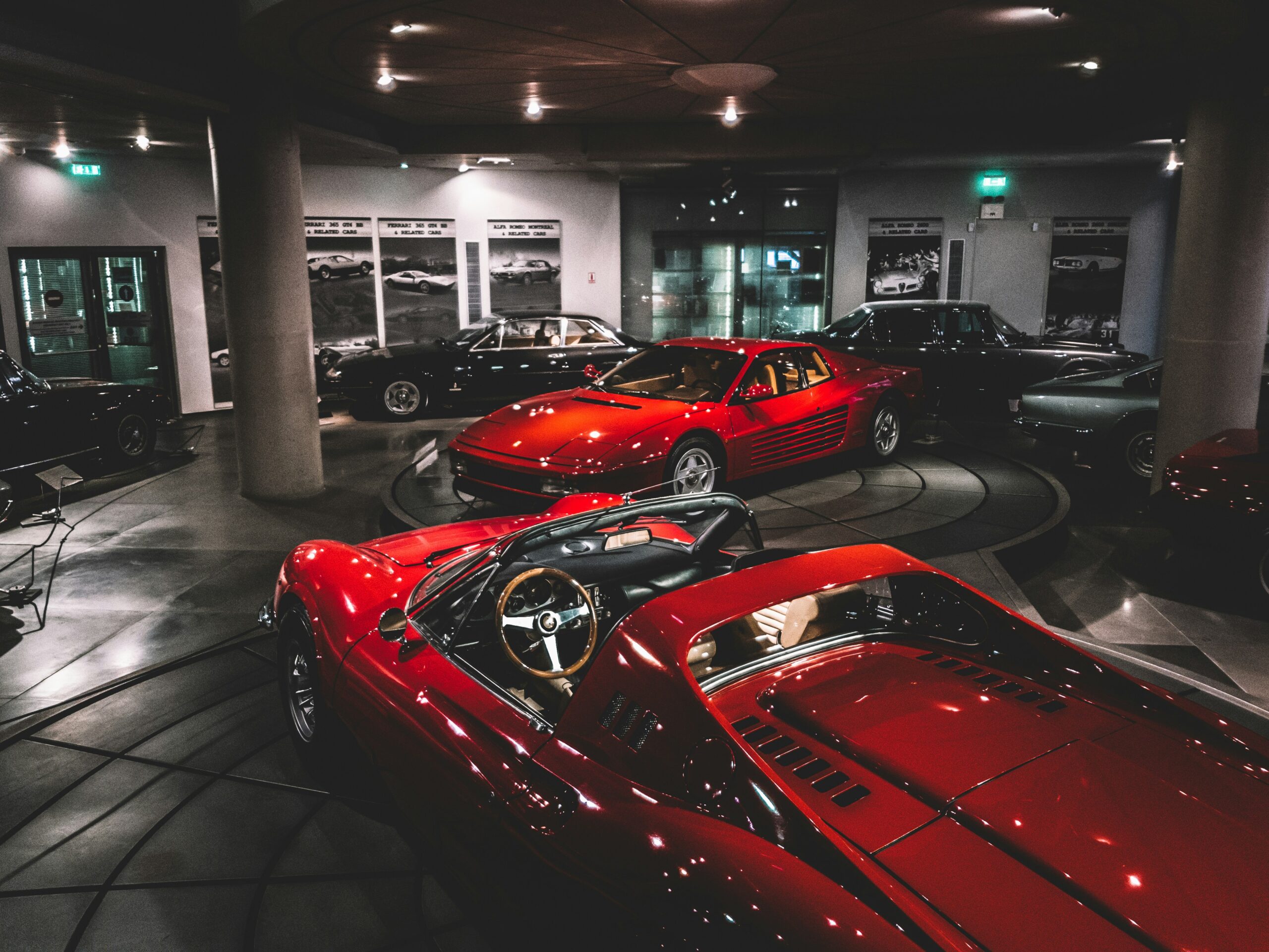 Red Ferrari sports cars on display in a museum setting.